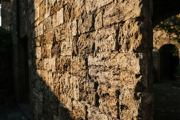 Muro in pietra di un cortile italiano illuminato dal sole radente